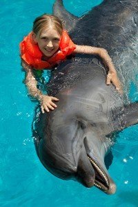 Little Smiling Girl Swimming With The Dolphin